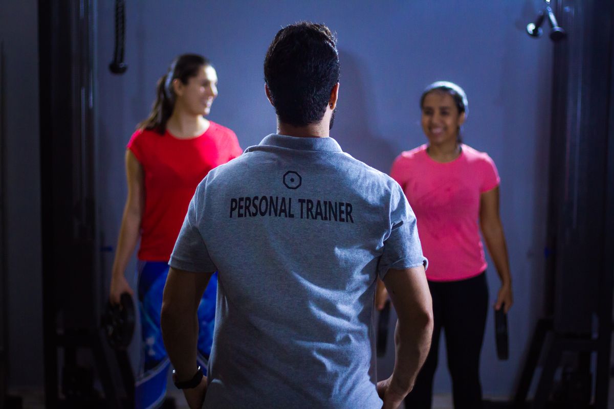 Entrenador personal guiando a dos clientas durante una sesión en el gimnasio